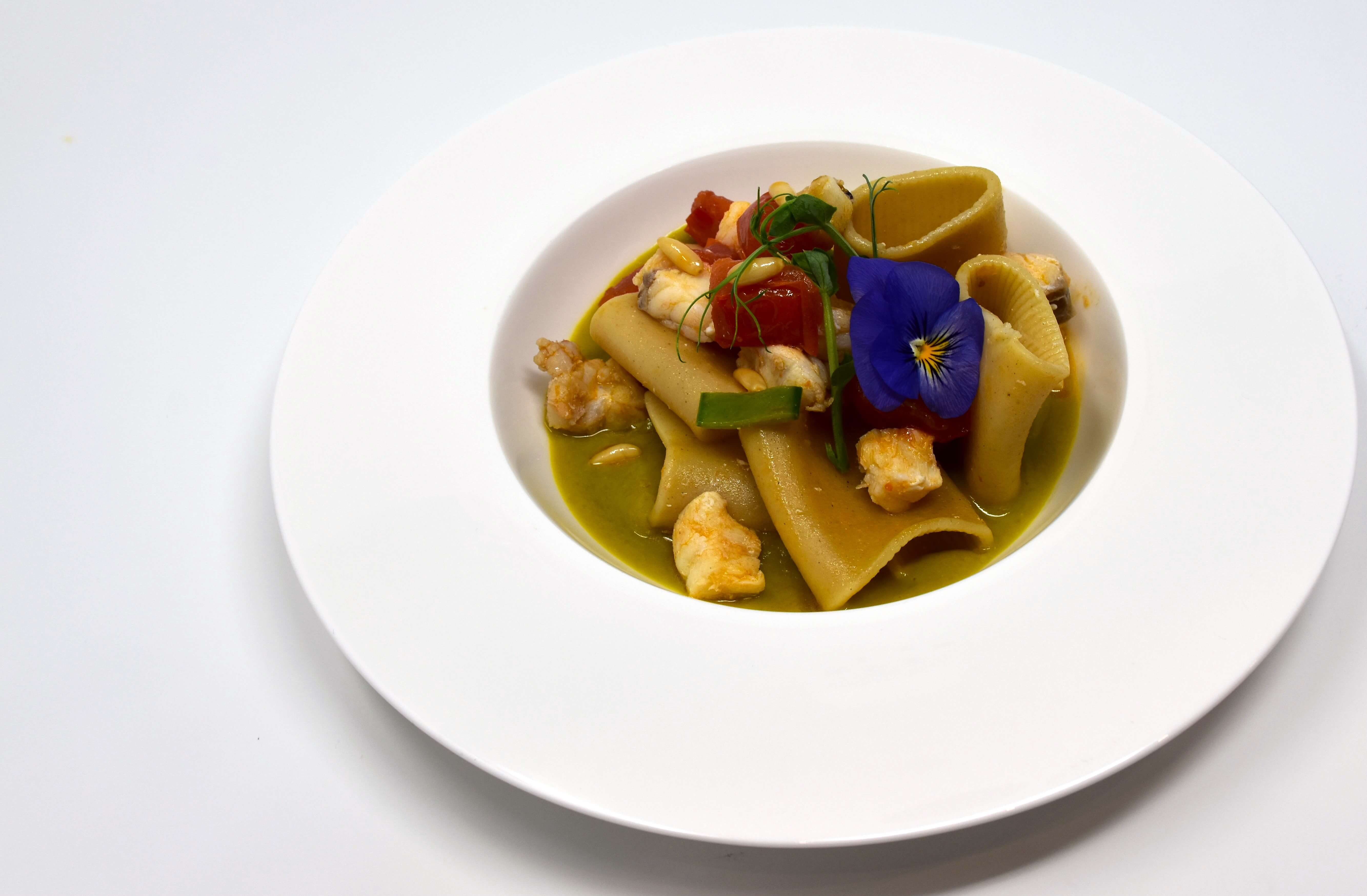 Paccheri con crema di pisellini, pescatrice cotta a bassa temperatura, pinolo di pino cebro, taccole,  pomodorino Pachino IGP saltato con cipolla ramata di Montoro e olio EVO di Sicilia aromatizzato al basilico