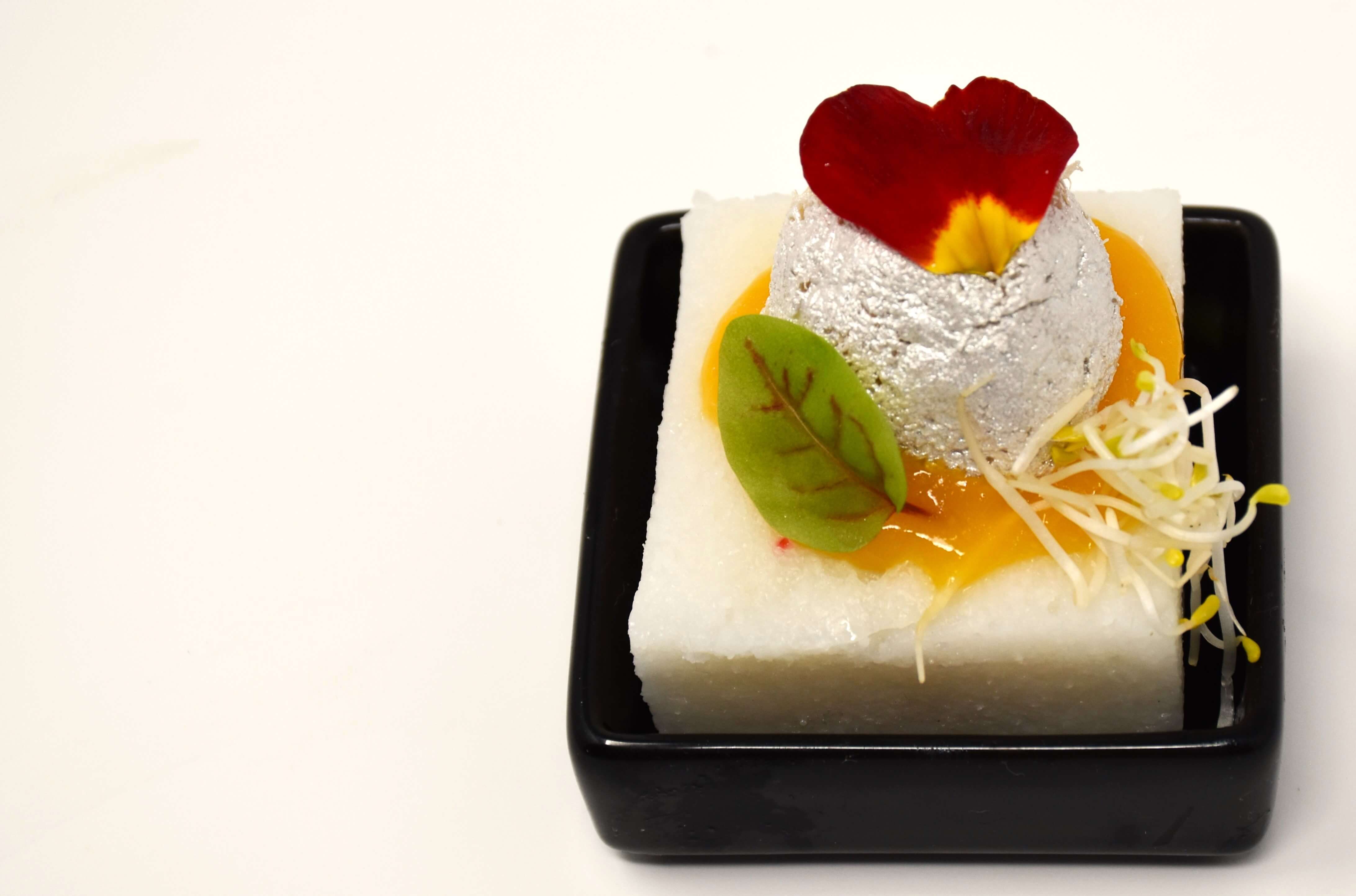 Polenta bianca con crema allo zafferano e baccalà mantecato ricoperto di argento edibile